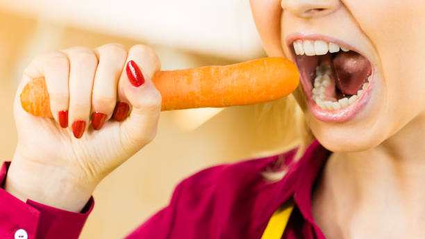 istock Woman holding biting carrot. 1053188338