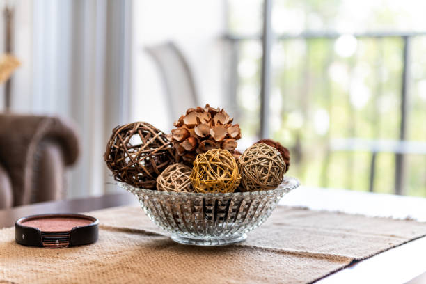 Modern, contemporary, clean decor with vase on table, tablecloths, coaster set, wicker balls and cone in apartment, home, house with bright light from window in living room