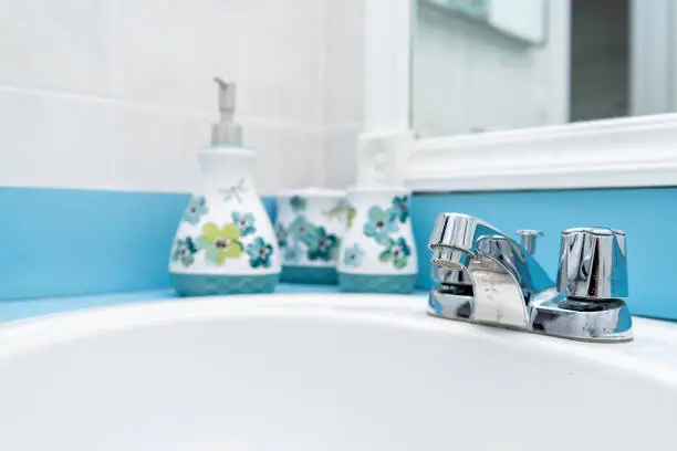 Closeup of blue, teal, turquoise modern, paint, painted bathroom tiled walls, mirror, sink, water faucet with liquid soap dispensers, vanity