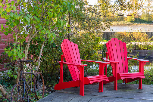 Two bright red adirondack chairs on a secluded patio