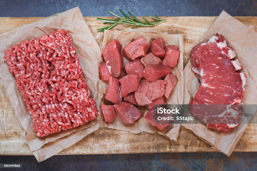 Fresh raw angus beef meat, whole, ground and chopped on parchment paper Fresh raw angus beef meat, whole, ground and chopped on parchment paper , wooden cutting board,  stone background, top view Red Meat Stock Photo