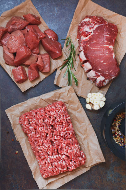 Assorted cuts of raw grass fed angus  beef meat on parchment paper Assorted cuts of raw grass fed angus  beef meat on parchment paper being prepared. Top view grass fed stock pictures, royalty-free photos & images