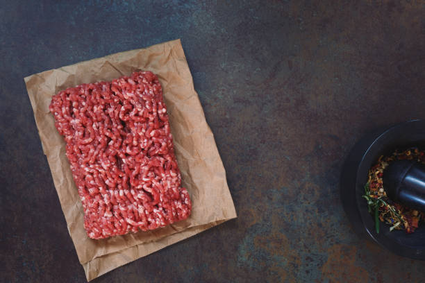 Fresh raw grass fed angus ground beef on parchment paper Fresh raw grass fed angus ground beef on parchment paper, concrete rustic background, blank space, top view grass fed stock pictures, royalty-free photos & images