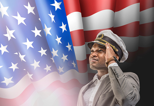 US boat captain saluting in front of American flag