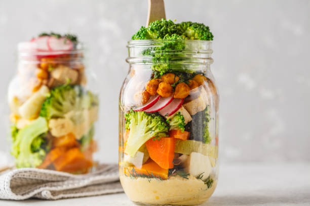 gesunde hausgemachte mason jar-salat mit gebackenem gemüse, hummus, tofu und kichererbsen. - salad vegetable pumpkin broccoli stock-fotos und bilder