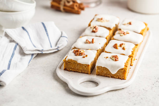 Vegan carrot cake with coconut cream and pecan, plant based diet concept. Vegan carrot cake with coconut cream and pecans on white board. Clean eating, healthy food, plant based diet concept. carrot cake stock pictures, royalty-free photos & images