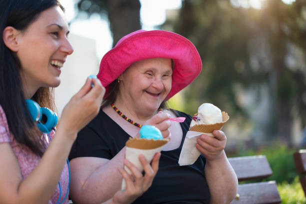 Woman with Down Syndrome and her friend eating ice cream and having fun Woman with Down Syndrome and her friend eating ice cream and having fun in a park. disabled adult stock pictures, royalty-free photos & images