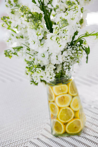 White flower bouquet in the vase which decorated with lemon slices for fresh air smelling