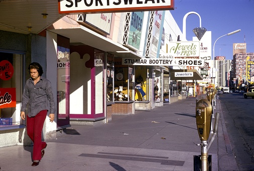 Las Vegas, Nevada, USA, 1977. The famous Fremont street in Las Vegas with shops, passers-by, billboards and golden parking meters.