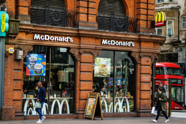 pedestrians passing in front of a mc donald's restaurant on the main street of london, united kingdom - brand name yellow red business imagens e fotografias de stock