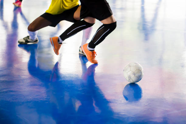 Futsal player  trap and control the ball for shoot to goal. Soccer players fighting each other by kicking the ball. Indoor soccer sports hall. Football futsal player, ball, futsal floor. Sports background. Youth futsal league. Indoor football players with classic soccer ball.
