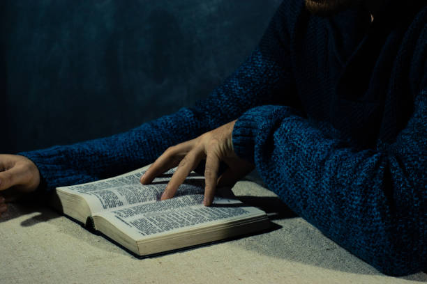 istock Young man sitting at a table reading the Bible 1053232422