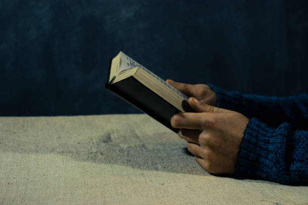 istock Young man sitting at a table reading the Bible 1053232522
