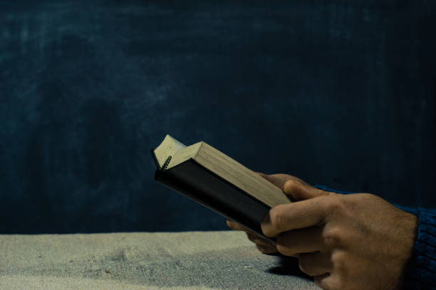 istock Young man sitting at a table reading the Bible 1053232694