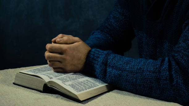 istock Young man sitting at a table reading the Bible 1053233180