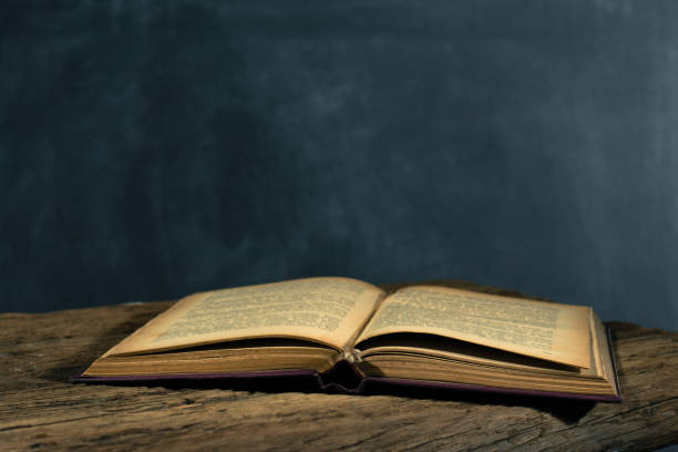 istock One open old book and three closing books on a white wooden table. Beautiful background. 1053235298