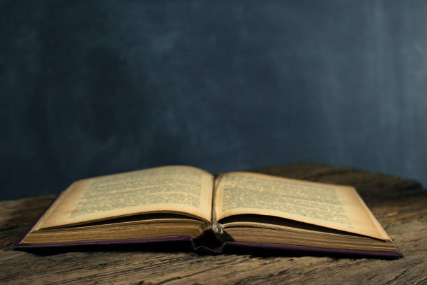 istock One open old book books wooden table. Beautiful background. 1053236466