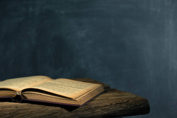 istock One open old book books wooden table. Beautiful background. 1053236598