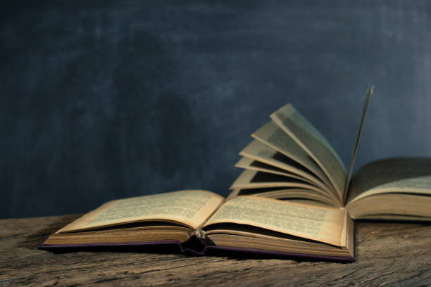 istock One open old book books wooden table. Beautiful background. 1053236704