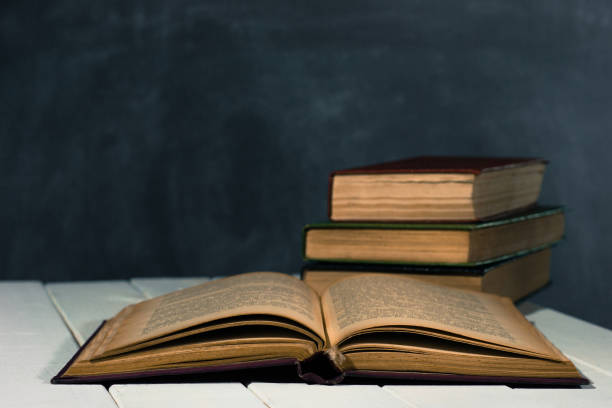 istock One open old book books wooden table. Beautiful background. 1053236884