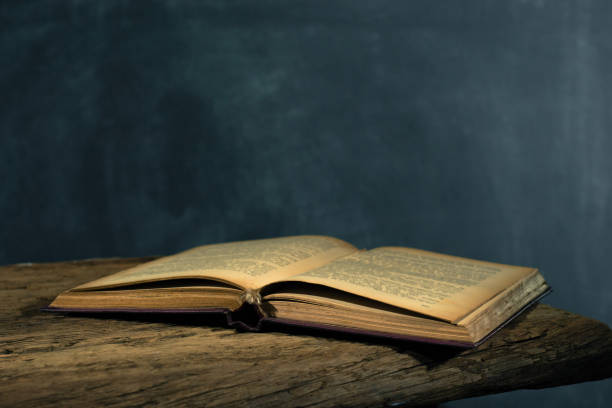 istock One open old book and three closing books wooden table. Beautiful background. 1053239258