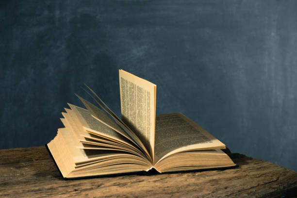 istock One open old book and three closing books wooden table. Beautiful background. 1053239286