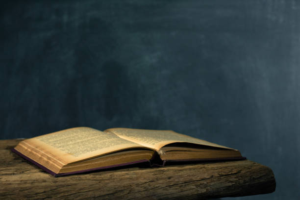 istock One open old book and three closing books wooden table. Beautiful background. 1053239506