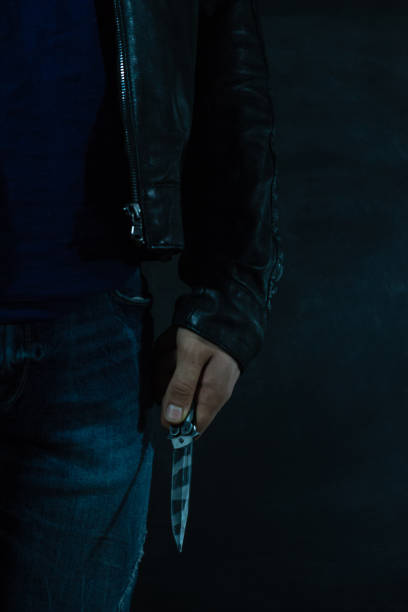 istock Young guy with a knife about to attack, over dark background. 1053239588