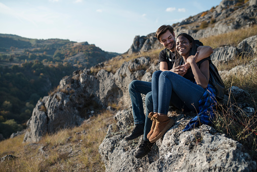 Young hiking couple resting on a rock in the nature ..