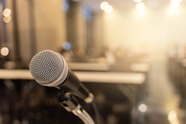 istock Microphone over the blurred business forum Meeting or Conference Training Learning Coaching Room Concept with noise, Blurred background. 1053256598