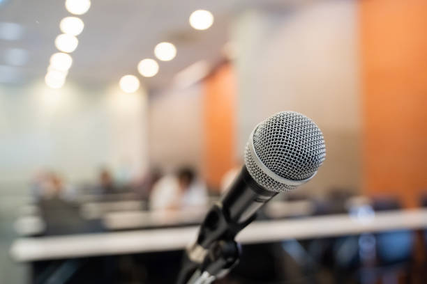 istock Microphone over the blurred business forum Meeting or Conference Training Learning Coaching Room Concept with noise, Blurred background. 1053256620