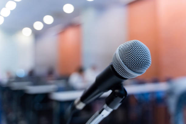 istock Microphone over the blurred business forum Meeting or Conference Training Learning Coaching Room Concept with noise, Blurred background. 1053256622
