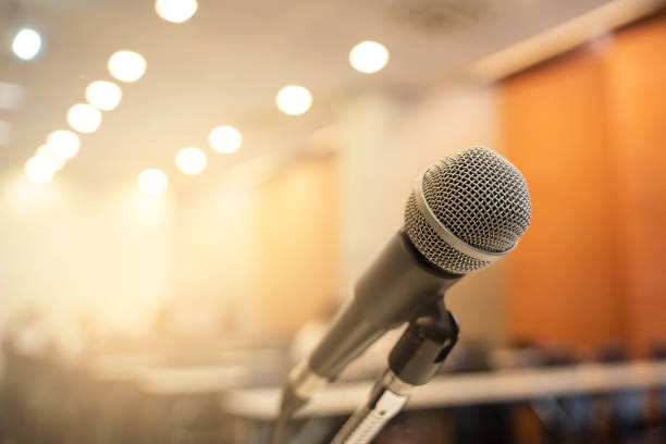istock Microphone over the blurred business forum Meeting or Conference Training Learning Coaching Room Concept with noise, Blurred background. 1053256636