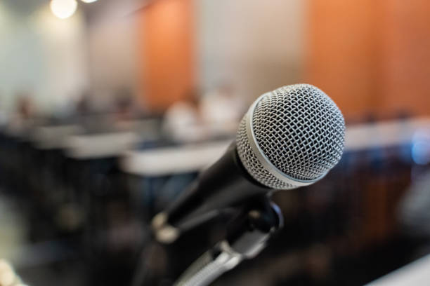 istock Microphone over the blurred business forum Meeting or Conference Training Learning Coaching Room Concept with noise, Blurred background. 1053256638