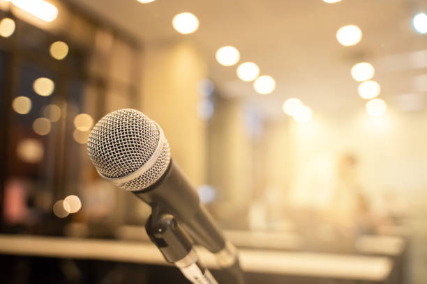 istock Microphone over the blurred business forum Meeting or Conference Training Learning Coaching Room Concept with noise, Blurred background. 1053256652