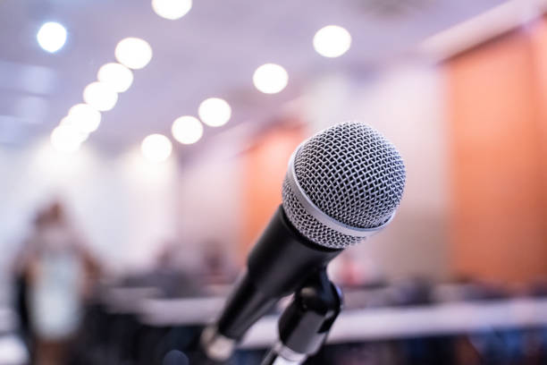 istock Microphone over the blurred business forum Meeting or Conference Training Learning Coaching Room Concept with noise, Blurred background. 1053256658