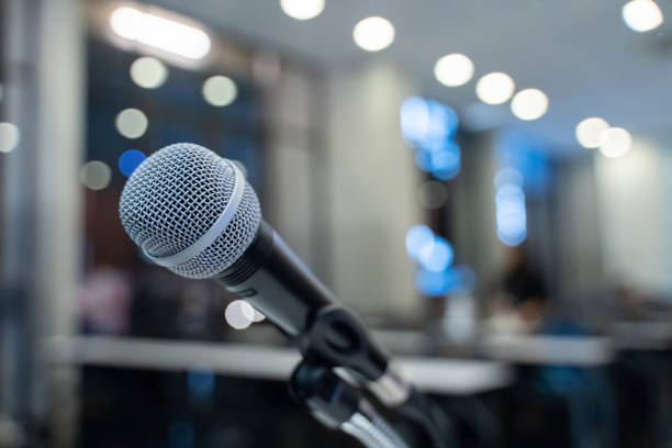 istock Microphone over the blurred business forum Meeting or Conference Training Learning Coaching Room Concept with noise, Blurred background. 1053256664
