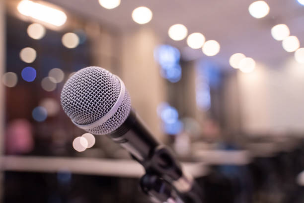 istock Microphone over the blurred business forum Meeting or Conference Training Learning Coaching Room Concept with noise, Blurred background. 1053256686