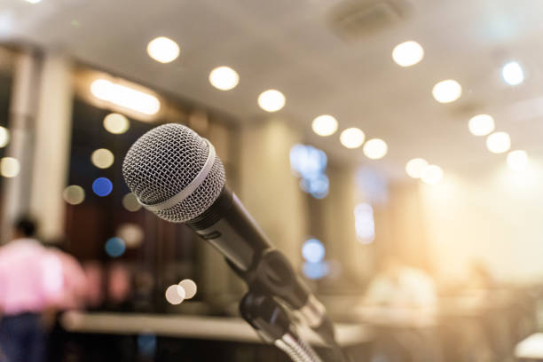 istock Microphone over the blurred business forum Meeting or Conference Training Learning Coaching Room Concept with noise, Blurred background. 1053256692