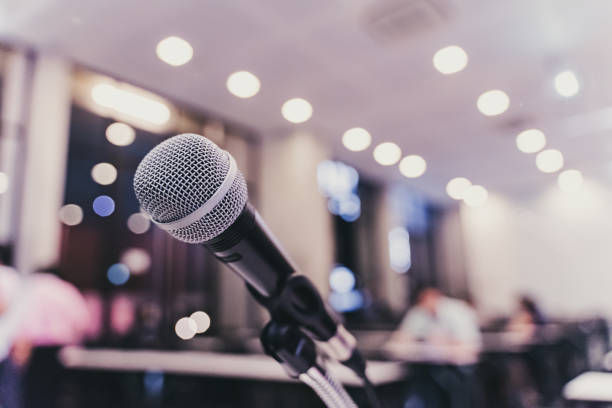 istock Microphone over the blurred business forum Meeting or Conference Training Learning Coaching Room Concept with noise, Blurred background. 1053256698