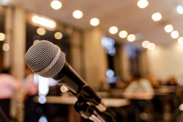 istock Microphone over the blurred business forum Meeting or Conference Training Learning Coaching Room Concept with noise, Blurred background. 1053256712