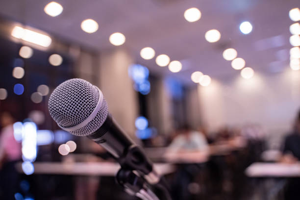 istock Microphone over the blurred business forum Meeting or Conference Training Learning Coaching Room Concept with noise, Blurred background. 1053256714