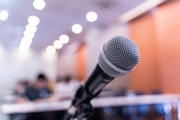 istock Microphone over the blurred business forum Meeting or Conference Training Learning Coaching Room Concept with noise, Blurred background. 1053256734