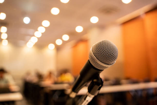 istock Microphone over the blurred business forum Meeting or Conference Training Learning Coaching Room Concept with noise, Blurred background. 1053256744