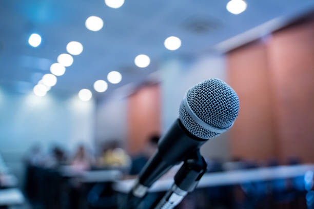 istock Microphone over the blurred business forum Meeting or Conference Training Learning Coaching Room Concept with noise, Blurred background. 1053256746