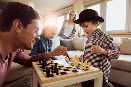 Young family enjoying time at home playing chess together