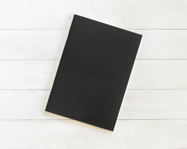 istock Book mockup blank black leather A4-size cover page template flat lay on white wood table from top view 1053261224