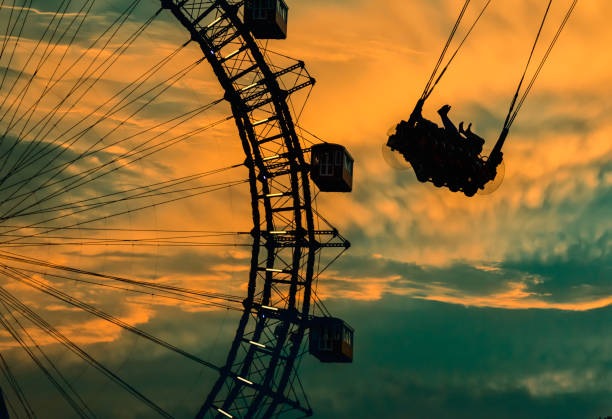 Silhouette of the ferris wheel and people on swing