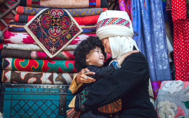 Kyrgyz mother and son at home Kyrchyn, Kyrgyzstan, 6th September 2018:  tender moment in between Kyrgyz mother and her son in their home yurt, dressed in traditional clothing kyrgyzstan photos stock pictures, royalty-free photos & images