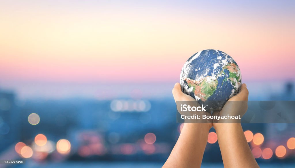 Sustainable community concept Human hands holding earth global over blurred city night background. Elements of this image furnished by NASA Globe - Navigational Equipment Stock Photo